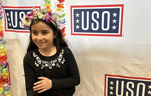 Victoria smiling in front of a USO banner.  