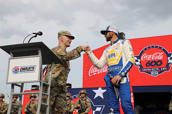 Service member fist bumping with NASCAR driver at Coke600 event