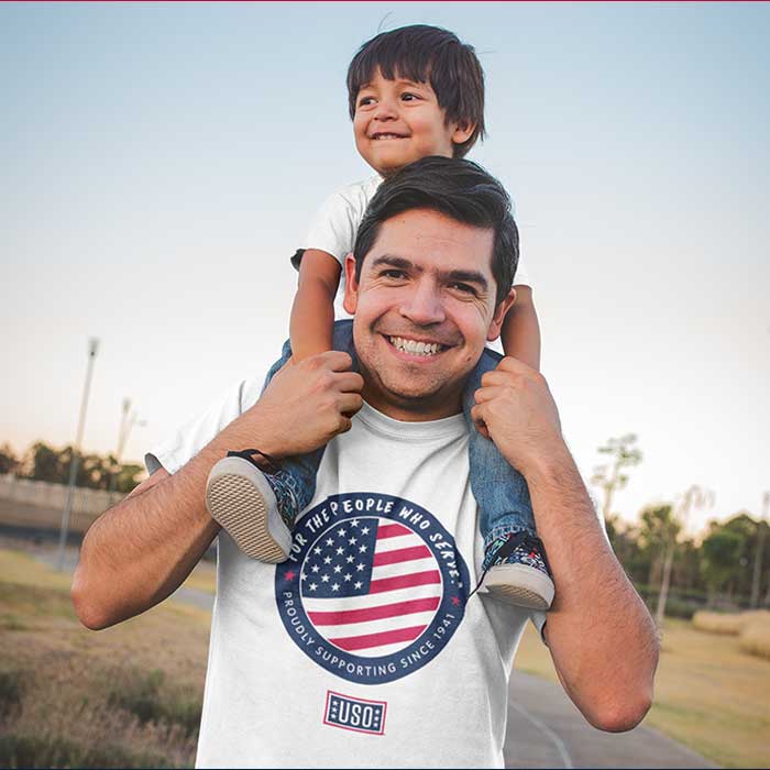 Photo of man wearing the 2024 USO T-shirt with a child on his shoulders