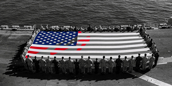 Large American flag being held by service members