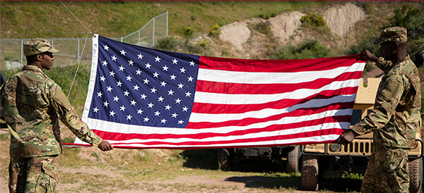 Servicemen hold American flag