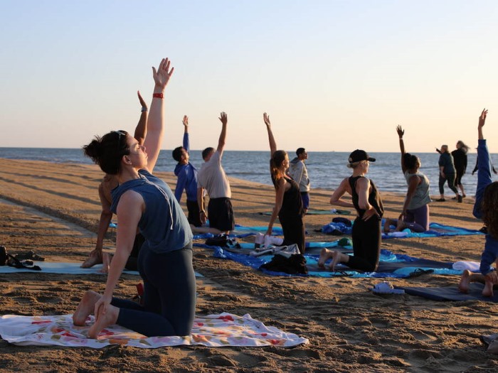 People doing yoga pose on the beach