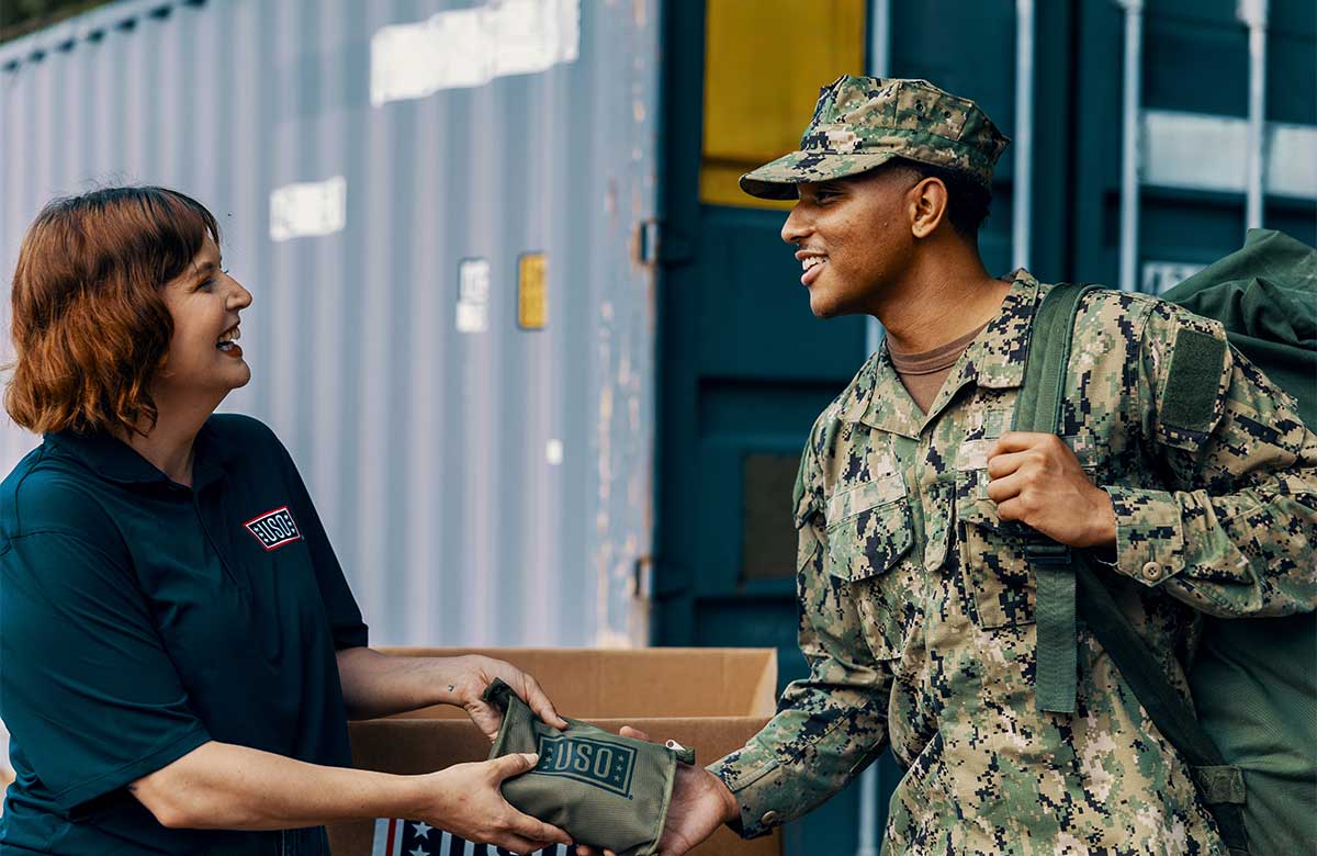 USO volunteer hands service member a USO care package.