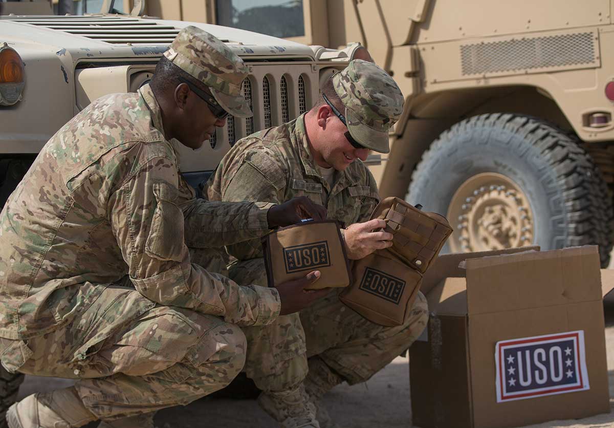 Service members pose with their USO care packages