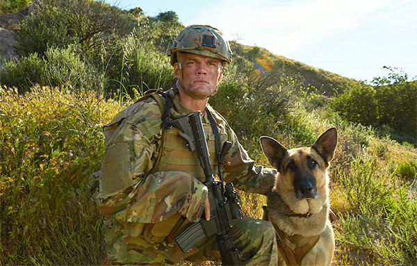 Service member and their K-9 stare into the camera.