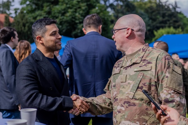 USO Global Ambassador Wilmer Valderrama shakes hands with service member at event in Warsaw, Poland.