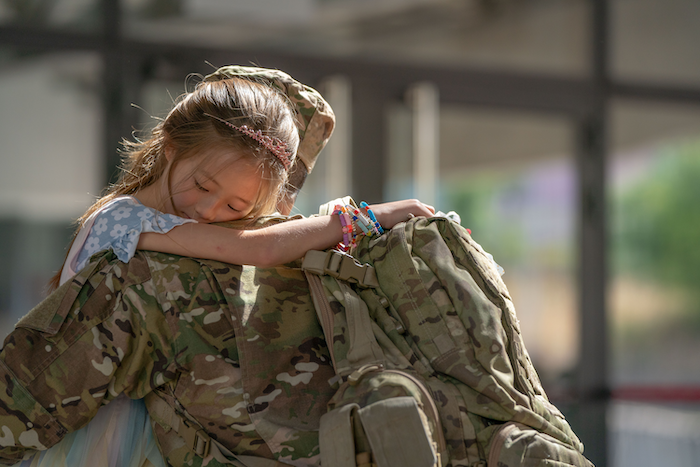 Service member holding a child in their arms