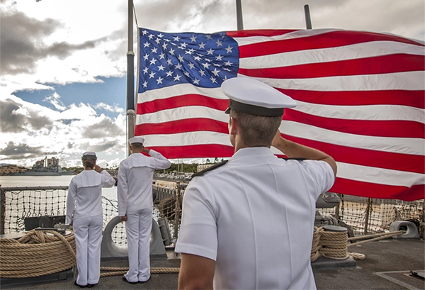 Service members salute American flag.