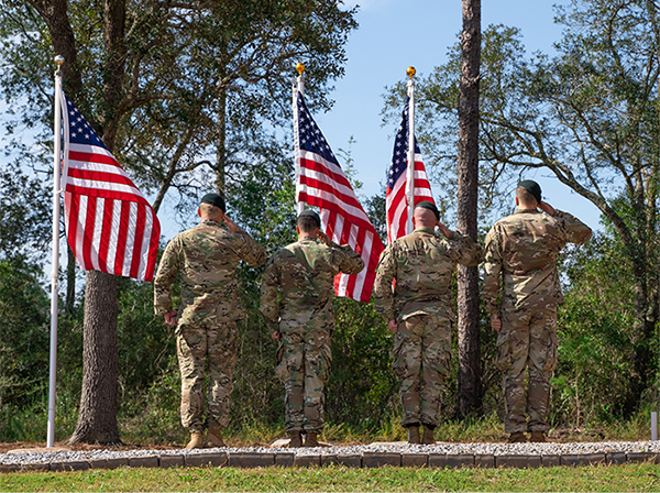 Service members salute American flags.