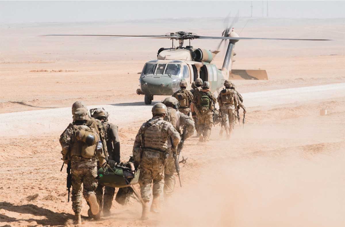 Airmen walking toward helicopter in desert.