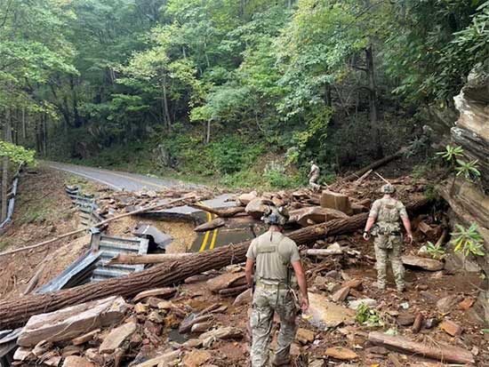 Service members walking along a road covered in debris