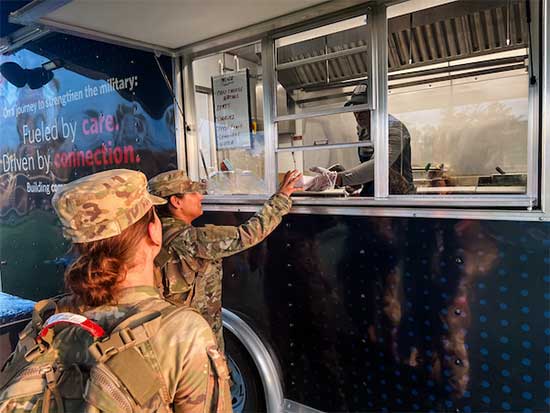 Two service members receiving food from a USO food truck