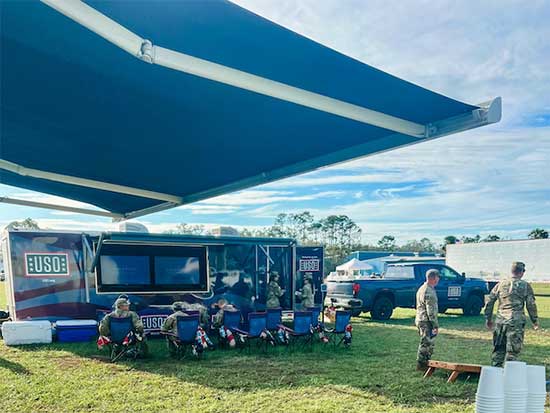 Group of service members in camping chair around a Mobile USO center van