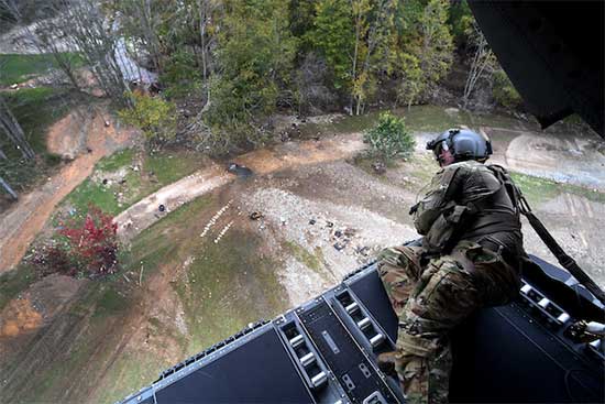 Service member laying down looking out the back of an aircraft at land impacted by Hurricane Helene