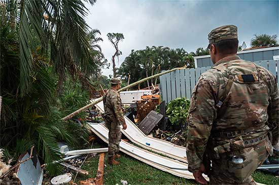 Service members survey damaged house