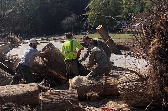 Service members cutting downed trees from road.