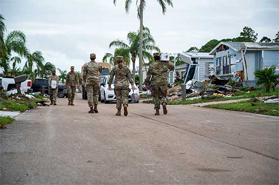 Service members delivering meals and water in damaged neighborhood