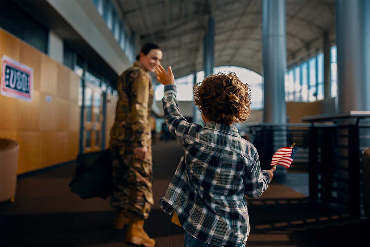 Child waves goodbye to service member.