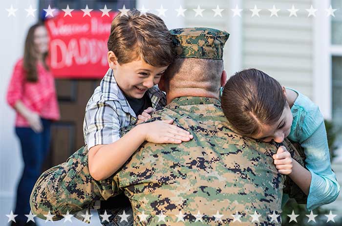 Children hug service member during welcome home celebration.