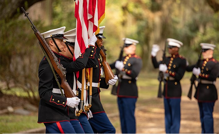 Marines carrying US flags and rifles.