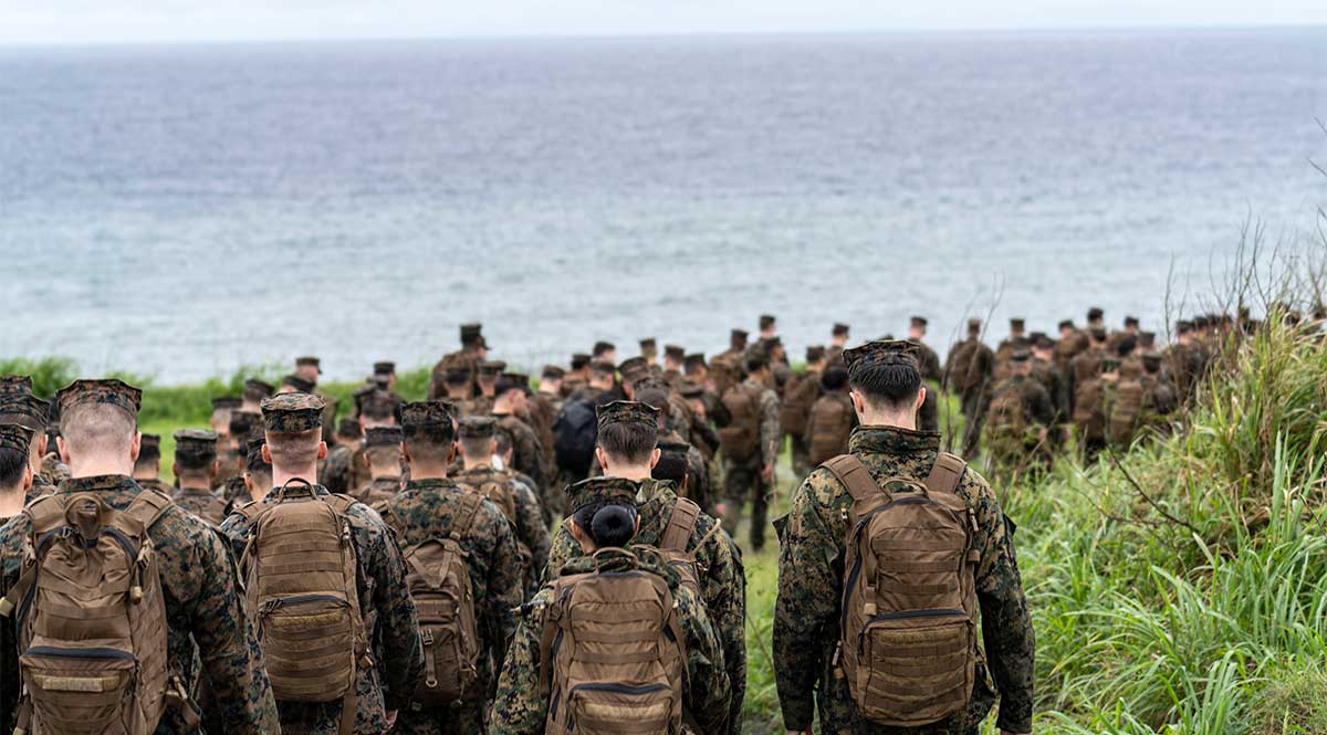 Service members walking along shoreline.