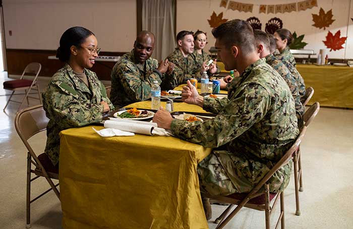 Service members enjoy a Thanksgiving meal around the table.