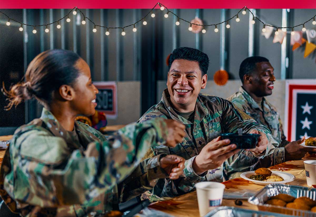 Photo of service members at a table passing food.