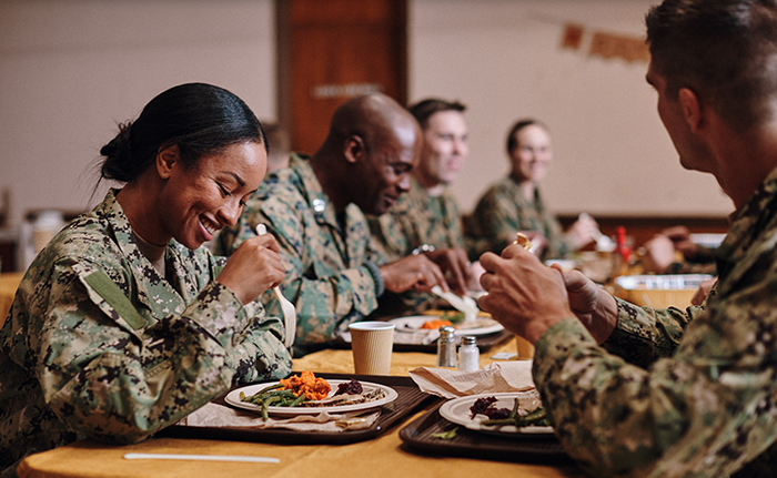 Service members gathered around a table enjoying a warm meal.