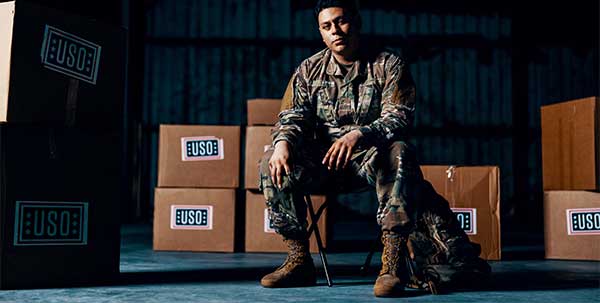 Solemn service member sitting in front of USO packages