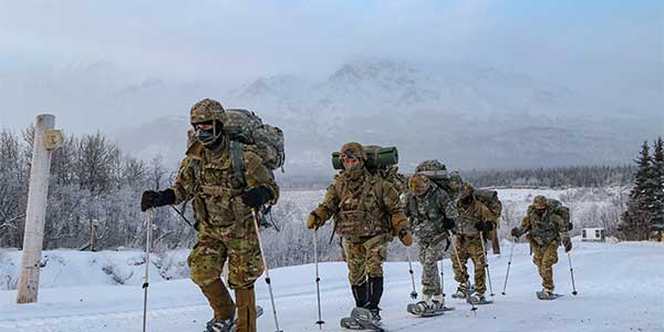 Five service members trekking through the snow