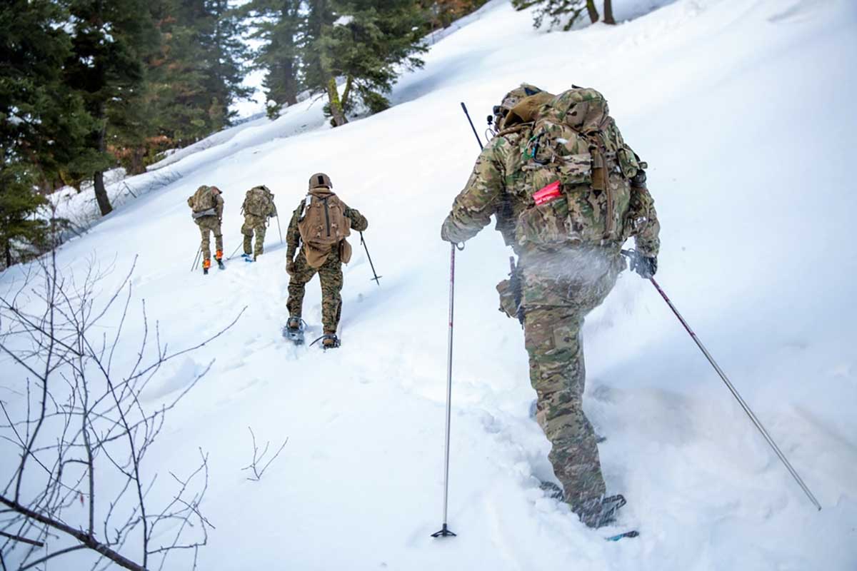 Service members hike through snowy forest