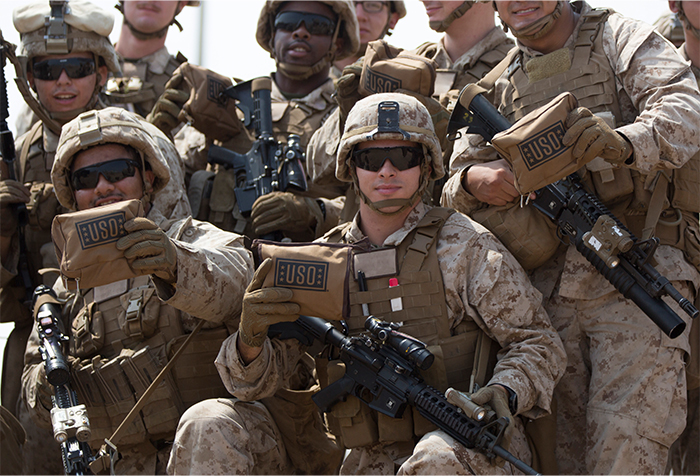 Service members pose with USO care packages.