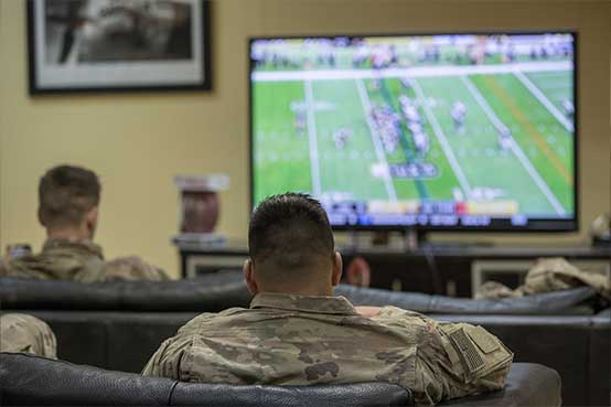 Service members watching a football game playing on tv.