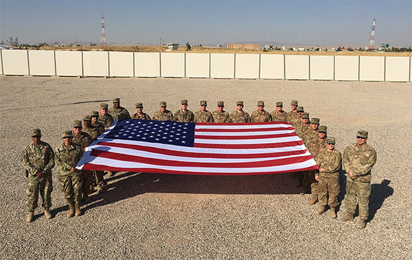 Service members stand with the flag.
