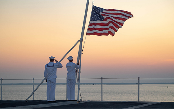 Service members stand with the flag.