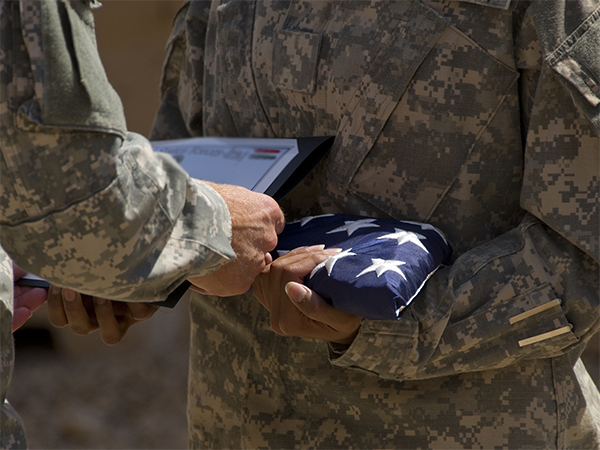 Service member holding a folded flag.