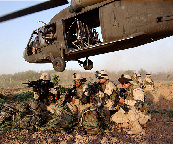 Service members at duty in front of a helicopter