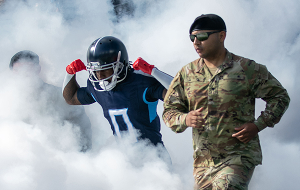 Service member and NFL player emerging from a foggy background