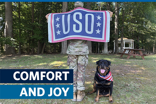 Service member with USO banner and canine support. graphic says: COMFORT AND JOY